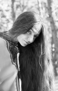 Uzun saçlı Ukraynalı kız ormanda işlenmiş ulusal bir gömlek giyiyor.