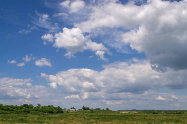 Büyük mavi bulutlu gökyüzünün altında küçük bir Ortodoks kilisesi.