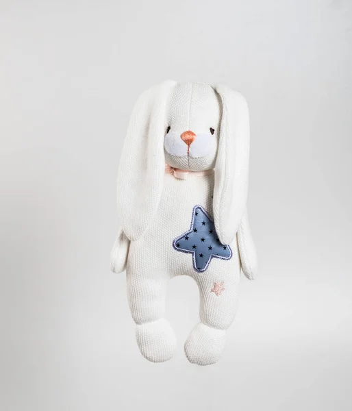 Soft toy rabbit with ears down and a star on his chest. Isolated on a white background.