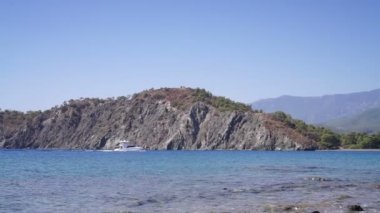 Keyifli tekne kayalık kıyılarda yüzüyor.