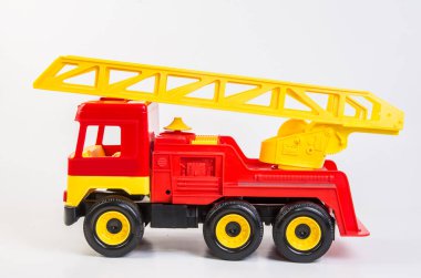 Beyaz arka planda çocuklar için çok renkli plastik oyuncak kamyonlar. Teleskopik antenli kırmızı itfaiye aracı.