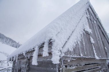 Karlı kış dağlarında bir ev.
