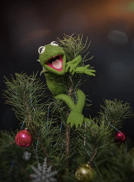 Green cheerful soft toy frog on the New Year tree.