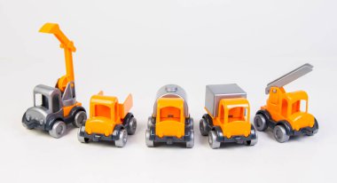 Construction vehicles lined up in a row. Multi-colored children's toys plastic trucks on a white background.