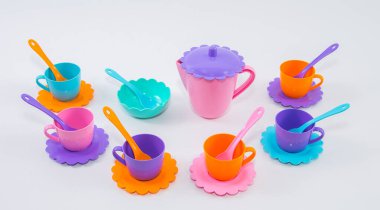 Beyaz arka planda çok renkli plastik tabak takımları olan çocuklar..