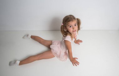 Pembe elbiseli küçük kız balerin jimnastik yapıyor..