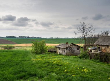 Baharda tarlaların arasında eski bir ahşap çiftlik.