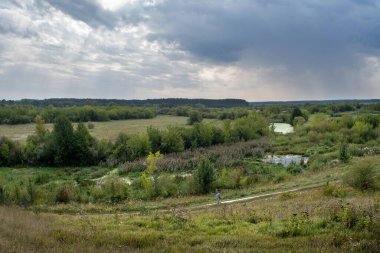 Scenic rural landscape with meadows, river and cloudy sky