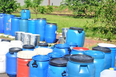 Satış için su depolamak için çeşitli renklerde kapaklı galonlar kullanılıyor. Bulanık arkaplan