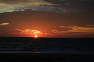 Bethany Sahili 'nde gün doğumu, Delaware. Sabahın erken saatlerinde güneş bulutları her türlü mavi ve turuncu tonuyla aydınlatıyor.