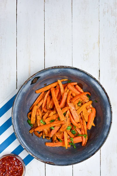 stock image Healthy vegetable carrot fries in an old enamel bowl, chili hot sauce on white boards. Top view