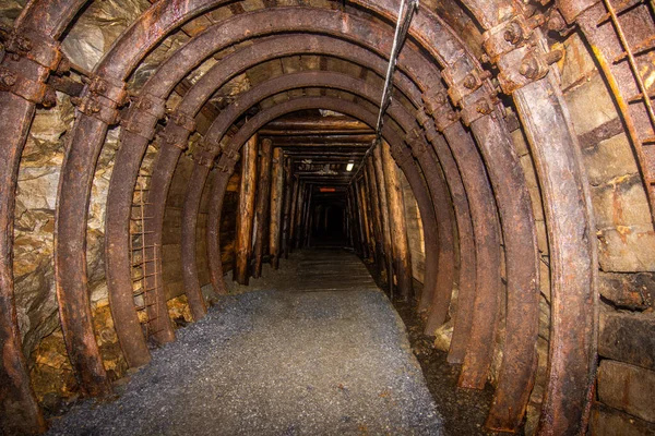 Abandoned old coal mine interior. Dangerous tunnels full of dirt and rusty equipment. Metal reinforcements.