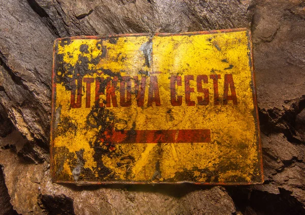Old rusty sign in the mine showing the escape route to the emergency exit.