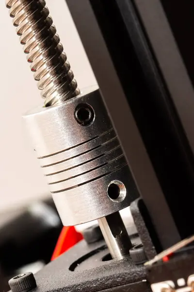 Detail of a flexible coupling connecting a motor shaft and a rod of a 3D printer. Vertical photo