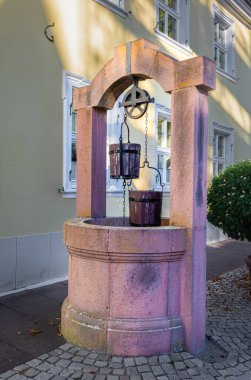 Ladenburg, Almanya 'da iki ahşap kovalı su makara sistemi olan eski Sandstone kuyusu.