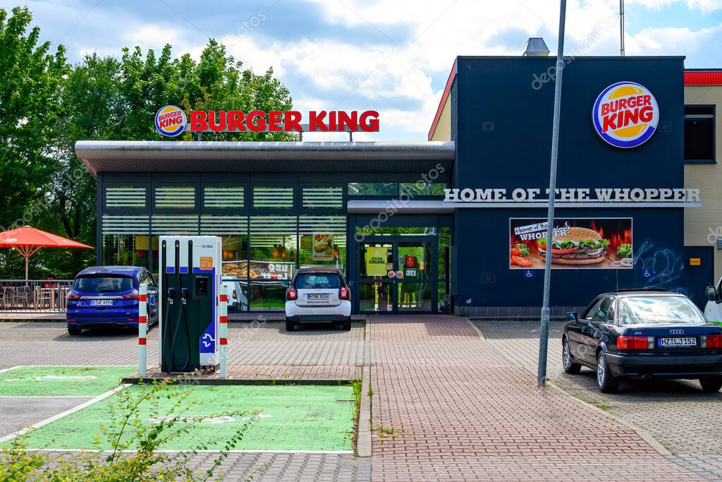Berlin, Germany - August 6, 2021: Entrance area of a fast food restaurant and charging station for electric cars in its parking lot.