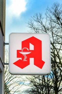 View to the sign of a pharmacy that is attached to a facade.