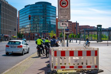 Berlin, Almanya - 8 Mayıs 2020: Berlin şehir merkezindeki Potsdamer Platz 'da bisiklet trafiği. Bisiklet filosundan iki polis memuru trafik ışığında bekliyor.. 
