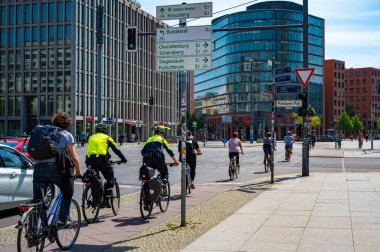 Berlin, Almanya - 8 Mayıs 2020: Berlin şehir merkezindeki Potsdamer Platz 'da bisiklet trafiği. Trafik ışıklarında, bisiklet filosundan iki polis yola çıktı.. 