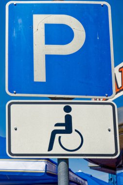 Bir otoparkta trafik levhası ve engelli park yerini gösteren ek bir tabela..