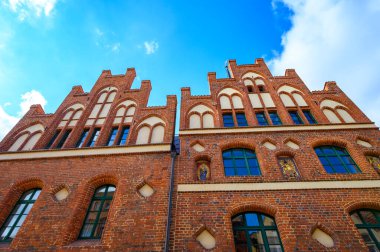 Bottom view to the brick facade of a historic building in Salzwedel, Germany, under a blue sky.