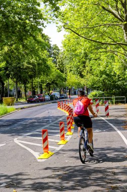 Berlin, Almanya - 30 Temmuz 2023: Yol güvenliğini artırmak için ana yolda özel bir bisiklet şeridinde bisikletçi.