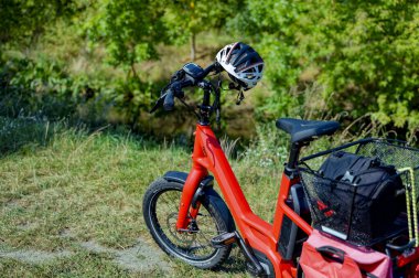 Wassmannsdorf, Almanya - 17 Eylül 2023: Bitki örtüsünün önündeki gidona bisiklet kaskı takılmış kırmızı bisiklet.