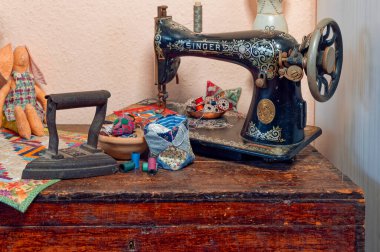 Berlin, Almanya - 16 Ocak 2024: Tarihi bir dikiş makinesi ve tarihi bir demir tezgahın ortasında duran ahşap sandık.