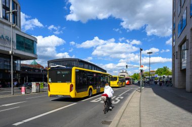 Berlin, Almanya - 27 Nisan 2024: Bisikletçi ve arka planda hayvanat bahçesi istasyonu bulunan çok sayıda toplu taşıma otobüsü.