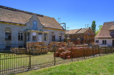 Eski bir çiftlik evinin restorasyonu. Bahçede çatının onarımı için yeni kiremitler ve ön cephenin eski tuğlaları var..