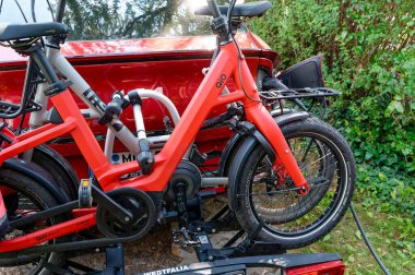 Berlin, Almanya - 20 Temmuz 2024: Bisikletli bir bisiklet parkı monte edilirken elektrikli araç pili şarj ediyor.