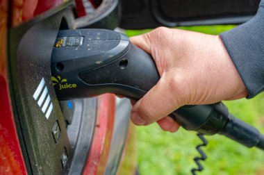 Berlin, Almanya - 24 Nisan 2024: Elektrikli bir arabanın şarj aletini takan bir adamın eli.