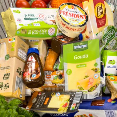 Berlin, Almanya - 13 Haziran 2024: Günlük ihtiyaçlar için çeşitli ürünlerle dolu bir alışveriş arabasına bakın.