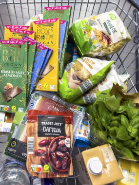 Berlin, Almanya - 17 Eylül 2024: Günlük ihtiyaçlar için çeşitli ürünlerle dolu bir alışveriş arabasına bakın.