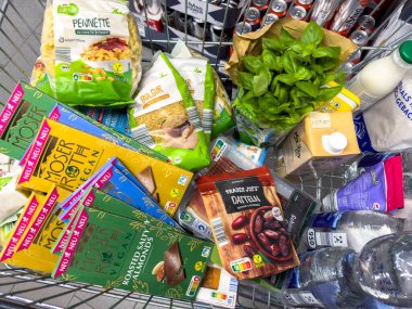 Berlin, Almanya - 17 Eylül 2024: Günlük ihtiyaçlar için çeşitli ürünlerle dolu bir alışveriş arabasına bakın.