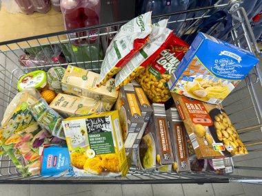 Berlin, Almanya - 9 Eylül 2024: Günlük ihtiyaçlar için çeşitli bakkaliyeleri olan bir alışveriş arabasına bakın.