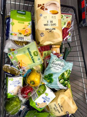 Berlin, Almanya - 12 Aralık 2024: Günlük ihtiyaçlar için çeşitli ürünlerle dolu bir alışveriş arabasına bakın.