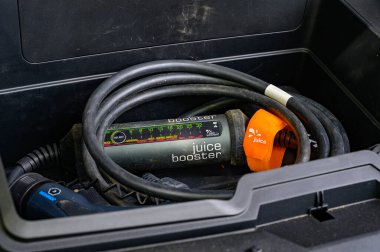 Berlin, Almanya - 24 Nisan 2024: Şarj etmek için adaptörlü elektrikli bir arabanın gövdesi.