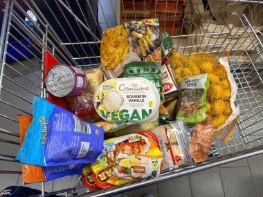 Berlin, Almanya - 16 Aralık 2024: Günlük ihtiyaçlar için çeşitli ürünlerle dolu bir alışveriş arabasına bakın.