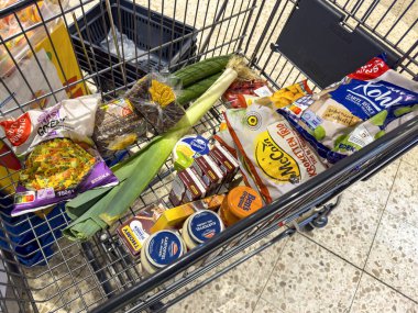 Berlin, Almanya - 19 Aralık 2024: Günlük ihtiyaçlar için çeşitli ürünlerle dolu bir alışveriş arabasına bakın.