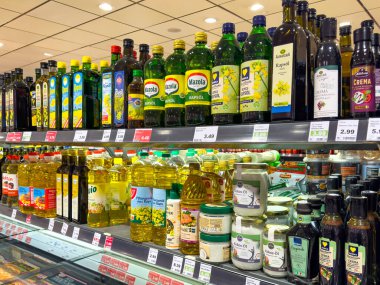 Berlin, Almanya - 19 Aralık 2024: Süpermarkette çeşitli şişelerde pişirme yağı bulunan raf. 