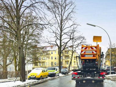 Berlin, Almanya - 14 Şubat 2025: Arkadan gelen kamyon, kış yolu bakımı için küçük bir araç taşıyor.