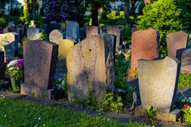 Mezarlıktaki birkaç mezar taşının arkasında. Kişisel veriler görülemiyor.