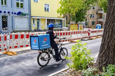 Berlin, Germany - July 27, 2025: Delivery driver of a pizza restaurant chain on a bicycle with a large delivery box.