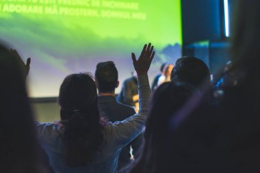 Kilise ayininde Tanrı 'ya şükreden bir kadının elleri havada.
