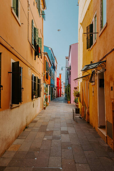 Burano, Italy - October 2022: Typical colorful houses in front of canal with boat in Burano