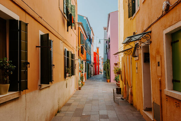 Burano, Italy - October 2022: Typical colorful houses in front of canal with boat in Burano