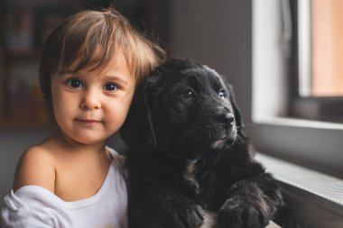 Sevimli küçük kız yavrusuyla sarılıp oynuyor.