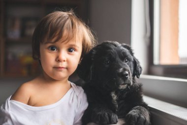 Sevimli küçük kız yavrusuyla sarılıp oynuyor.