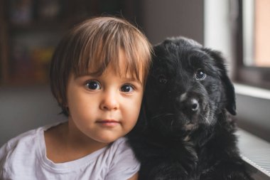 Sevimli küçük kız yavrusuyla sarılıp oynuyor.